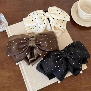 Lot de trois pinces à cheveux en satin à pois et perles sur un fond rustique élégant