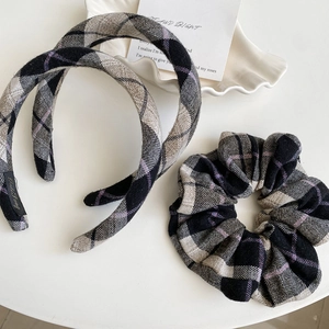 Detail view of plaid velvet headband and scrunchie set on minimalist ceramic tray