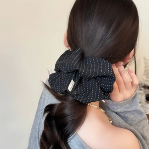 Elegant large black polka dot scrunchie with a handmade label on a ponytail