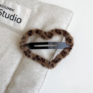 Close-up detail of plush leopard print heart hair clip with durable black metal BB grip