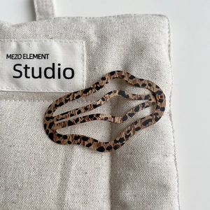 Detail of wavy leopard print hair clip with tortoiseshell pattern on canvas fabric