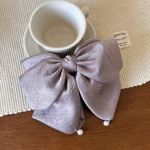 Détail de la pince à cheveux à nœud en satin violet avec d'élégantes perles pendantes