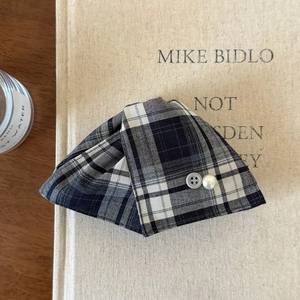 Detail of checkered fabric hair claw with vintage button and faux pearl on a book