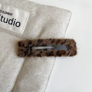Detail shot of plush leopard print BB hair clip on textured fabric background