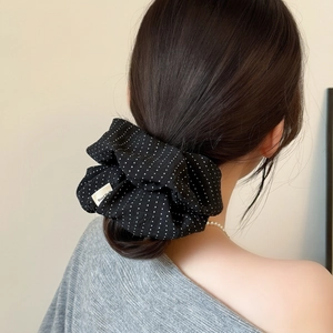Elegant black polka dot scrunchie with handmade tag on a low bun hairstyle