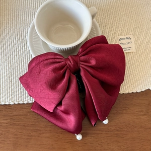 Vue détaillée du grand nœud papillon en satin bordeaux avec pendentifs en perles