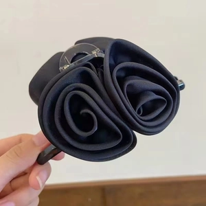 Détail de la pince à cheveux rose en satin noir montrant la texture élégante des pétales