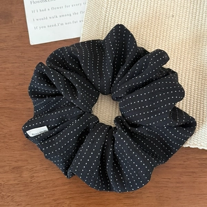 Elegant black polka dot hair scrunchie with handmade tag on natural wooden background
