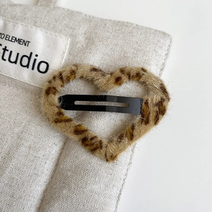 Detailed macro view of heart-shaped plush leopard print hair clip with metal BB grip