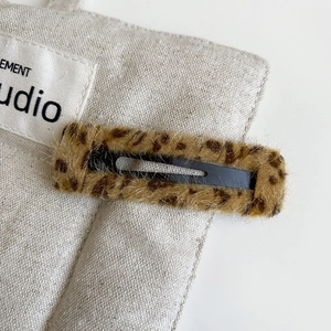 Close-up detail of leopard print plush hair clip with soft faux fur and black metal BB base