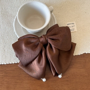 Détail d'une grande pince à cheveux nœud en satin marron avec pendentifs en perles
