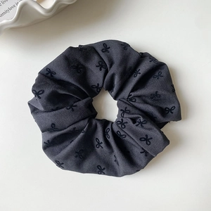 Detailaufnahme von dunkelgrauem Scrunchie aus Twill mit schwarzer Bogenstickerei