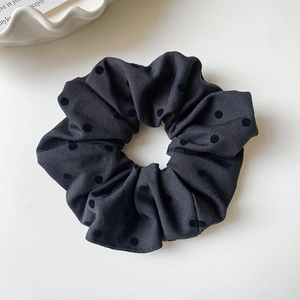 Makro-Detail eines dunkelgrauen Oversize-Scrunchies mit eleganten beflockten Polka-Dot-Mustern