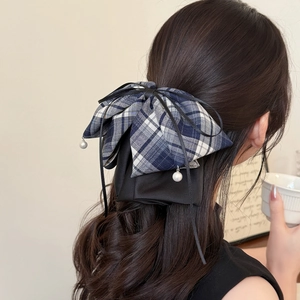 Detail of blue plaid bow hair claw with black silk ribbons and pearl pendants on hair