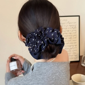 Chouchou géant bleu marine à fleurs blanches porté sur un chignon pour un look doux