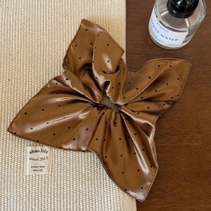 Détail d'un chouchou en satin de soie à pois avec grand nœud sur fond en bois rustique