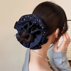 Détail d'un chouchou bleu marine à volants avec motif floral sur un chignon