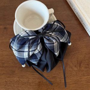 Detail of navy plaid bow hair claw with elegant long ribbons and pearl pendants