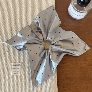 Détail d'un chouchou en satin gris à pois avec texture soyeuse et plis élégants raffinés
