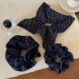 Ensemble de chouchous à fleurs bleu marine avec grand nœud sur un tapis beige chic