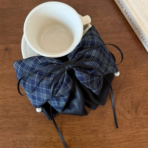 Detailed view of checkered bow hair clip with black satin layers and white pearl charm