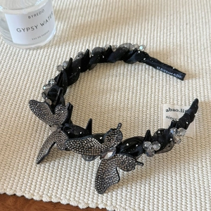 Détail du serre-tête papillon noir fait main avec des strass étincelants et des perles fines