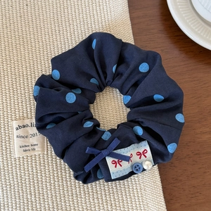 Gros plan d'un chouchou à pois bleu marine avec un nœud rouge et une perle