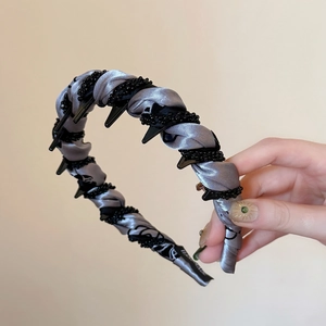 Détail du serre-tête en satin avec dents antidérapantes et tissage de perles noires