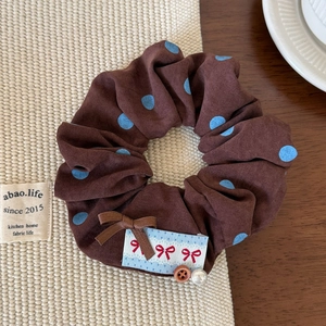 Vue détaillée du chouchou marron à pois avec rubans, perles et breloques de nœuds élégants