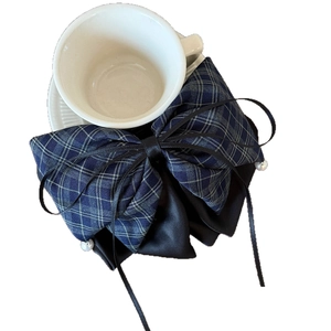 Elegant navy plaid bow hair clip with black ribbons and white pearls on white cup