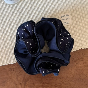 Gros plan sur chouchou bleu marine à fleurs blanches avec texture tissée élégante
