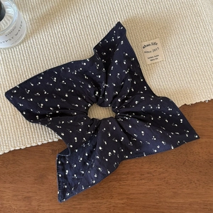 Détail d'un chouchou bleu marine à motif floral avec des coutures et une texture de qualité