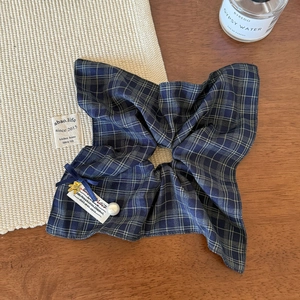 Detail of dark blue plaid scrunchie with bow, pearl pendant and Love charm on wood