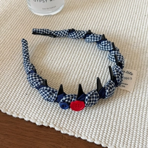 Détail d'un serre-tête fait main en tissu à carreaux bleus avec des boutons colorés