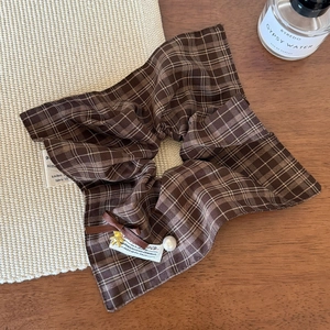 Close-up of brown plaid scrunchie with a gold bear pendant and elegant pearl detail
