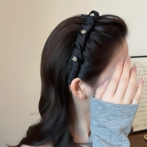 Elegant black twisted headband with sparkling rhinestones worn by a model in a side view