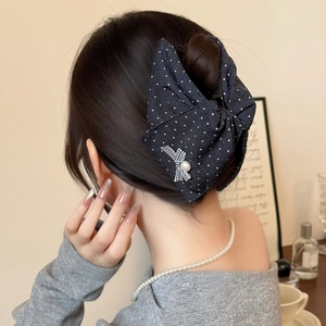 Pince à cheveux noeud bleu marine à pois avec perle sur chignon élégant