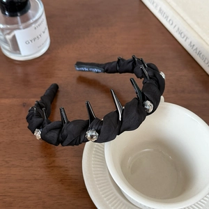 Elegant black twist headband with crystal studs and punk spikes in lifestyle setting