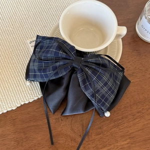 Navy plaid and black satin hair claw clip with pearl charm on a cozy wooden table