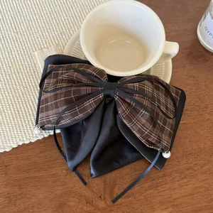 Detail of a plaid and satin bow hair claw with elegant pearls and ribbons on a white saucer