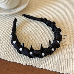 Detail of slim black pearl headband with non-slip teeth and stylish devil ear accents
