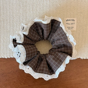 Détail d'un chouchou rétro à carreaux marron avec des bords en dentelle blanche délicate