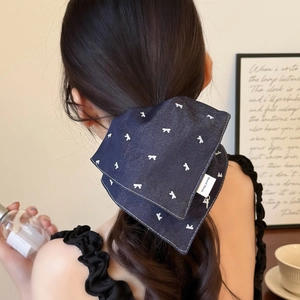Navy blue denim bow scrunchie with white prints and handmade label on hairstyle