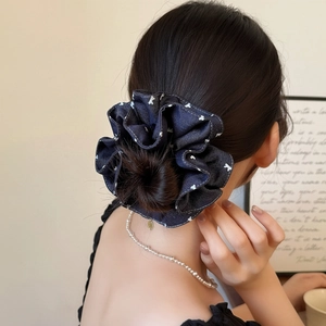 Detail view of navy blue polka dot scrunchie with denim texture on messy bun hairstyle