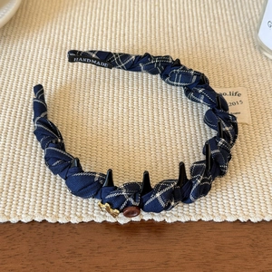 Détail d'un serre-tête vintage à carreaux bleus avec dents antidérapantes et breloque