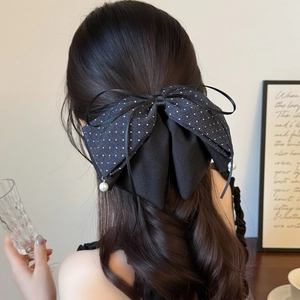 French style polka dot bow hair claw with pearl pendants shown on back of model hair