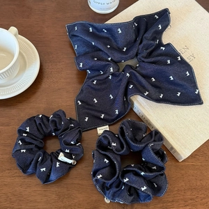 Handmade navy blue denim scrunchies with white bunny pattern on a vintage wooden desk