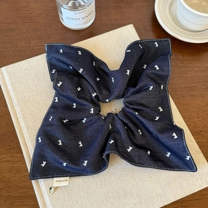 Detail of navy polka dot scrunchie with hand made tag on top of vintage book and perfume