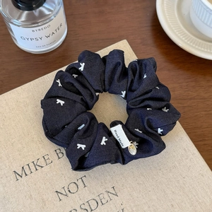 Navy blue polka dot scrunchie with white bows and gold charm on vintage books