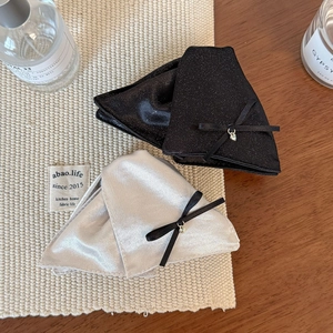 Détail de pinces à cheveux à nœuds en satin avec breloques cœur sur fond texturé